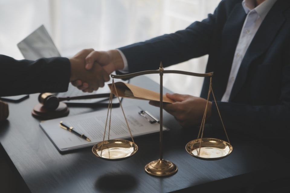 Hombre de negocios se dan la mano junto a una balanza